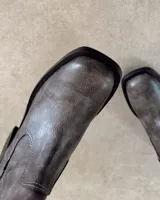 Bota de caña media color gris con punta cuadrada y elástico lateral.