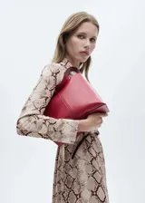 Vestido midi de corte recto con cuello camisero y cierre frontal de botones. Confeccionado en tejido fluido con estampado de serpiente, presenta mangas largas con puños abotonados, bolsillos de parche y trabillas para cinturón.