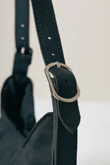 Cartera tipo hobo de diseño minimalista en color negro, con correa ajustable y cierre superior.