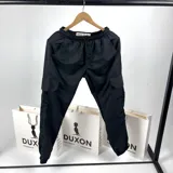 Pantalón cargo negro de nylon con cintura elástica ajustable con cordón, bolsillos laterales y puños elásticos en los tobillos.