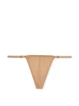 Panty tipo tanga en tono praline, confeccionado con microfibra suave de tiro bajo, con tirantes ajustables y herrajes dorados.