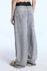 Jean de denim color gris con calce barrel, de pierna levemente bombé y pinzas a la altura de la rodilla. Presenta cierre frontal con botón y bolsillos laterales.