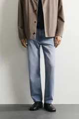 Pantalón de jean corte slim fit con efecto lavado, tiro medio, cinco bolsillos y cierre frontal con cremallera y botón.