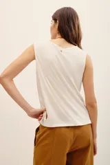 Musculosa de viscosa color blanco, sin mangas, con escote en V decorado con apliques y un gran estampado frontal de temática astrológica en tonos dorados y oscuros.