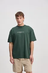 Remera oversize de manga corta color marrón con estampa pequeña en el pecho y estampa geométrica en la espalda.