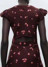 Vestido midi de color bordó con estampado de flores rosas, presenta un diseño entallado con cuello escotado y mangas cortas abullonadas, incluye cierre de cremallera lateral y abertura en la espalda.
