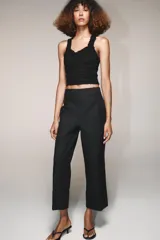 Pantalón marrón de tiro alto con bolsillos delanteros y traseros. El bajo está acabado con vuelta. Cierre frontal con cremallera y ganchos metálicos.