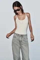 Jeans de tiro alto, pernera recta y larga, estilo clásico con cinco bolsillos, cierre frontal con cremallera y botón metálico.