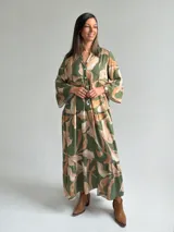Vestido largo verde con estampado botánico en tonos tostados, escote en V con botones frontales, mangas largas abullonadas y diseño en niveles con volados.