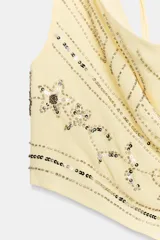 Top halter color amarillo claro con escote drapeado, detalle de abalorios y lentejuelas con brillo y cierre ajustable en el cuello y la espalda.