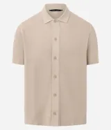 Camisa de punto de manga corta en color beige, con cuello inglés y cierre frontal de botones. Presenta una textura tejida y un corte regular que ofrece un ajuste cómodo y clásico.
