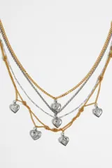 Collar de múltiples cadenas doradas y plateadas con dijes en forma de corazón con motivos grabados. Cierre de mosquetón.