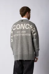 Sweater oversize de tejido de punto en color gris, con cuello redondo, puños y ruedo acanalados con detalles de desgaste. Presenta un diseño minimalista con logo tejido en la espalda.