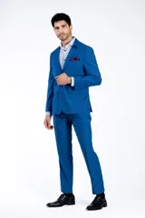 Traje de dos piezas compuesto por saco y pantalón de vestir en color azul brillante. El saco presenta solapas clásicas, cierre frontal de dos botones y bolsillos con solapa. El pantalón es de corte recto y tiro medio.