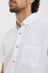 Camisa azul de manga corta, con cuello abotonado y bolsillo en el pecho.