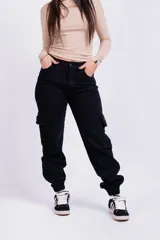 Pantalón mom cargo de jean negro con bolsillos laterales y tobillos ajustados.