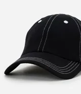 Gorra de sarga de algodón color negro con costuras decorativas en hilo blanco contrastante. Presenta visera curva, ojales bordados y ajuste posterior mediante hebilla metálica.