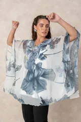 Blusa tipo túnica de gasa semitransparente con escote en V y mangas amplias. Presenta un diseño estampado con efecto acuarela en tonos azules, grises y marrones sobre fondo blanco.