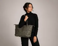 Cartera tipo tote bag de cuero vacuno color marrón oscuro, de diseño estructurado con asas largas para llevar al hombro y cierre superior. Presenta detalles de costuras decorativas y pespuntes en el frente.