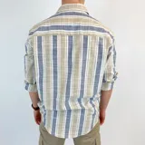 Camisa de cuello italiano, semi entallada, con rayas verticales en tonos azul, beige y blanco.