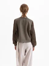 Buzo de calce regular con cuerpo de tela lisa y mangas largas de tejido calado con textura. Presenta escote redondo y puños ajustados.