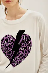 Remera de manga larga color blanco con estampa frontal de un corazón con diseño animal print en tonos violeta y negro, atravesado por un rayo negro.