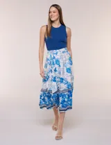 Vestido midi combinado de la marca Figueroa & Flower, con torso de modal azul sin mangas y cuello redondo, y falda evasé de rayón con estampado floral y paisajes en tonos blancos y azules, con cintura elastizada y lazo para anudar.