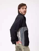 Rompevientos Rusty con cierre frontal, capucha y diseño de bloques de color en gris y verde militar. Cuenta con puños elásticos y logo de la marca en el pecho.