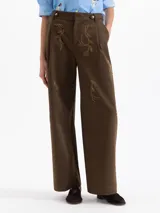 Pantalon de corte recto y tiro alto en color marron, con detalle de bordado en pedreria dorada sobre el frente. Presenta cierre frontal con botones y bolsillos laterales.