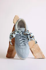 Zapatillas bajas color marrón con cordones y charms dorados.