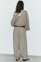 Pantalón de tiro medio con estampado de cuadros vichy en tonos beige y marrón. Cuenta con cintura elástica tipo nido de abeja y bajo ajustable con cordones.