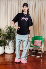 Remera negra de algodón con estampa de un perro con el logo de la marca en color rosa.