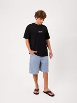Remera blanca Rusty de corte holgado, con cuello redondo y mangas cortas. Presenta un estampado en la espalda de estilo veraniego con palmeras, una tabla de surf y letras alusivas a la marca.