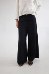 Pantalón de tiro medio-alto con piernas anchas y corte recto. Presenta cierre frontal con botón, bolsillos laterales y detalles de costuras verticales. Confeccionado en tencel.