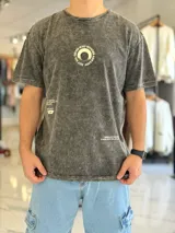 Remera oversize de color celeste con efecto gastado acid wash, mangas cortas y cuello redondo. Cuenta con un gran estampado circular en la espalda con la frase "Not all those who wander are lost" y texto adicional debajo.