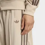 Pantalón deportivo Adidas modelo Firebird de corte holgado y tiro medio. Presenta diseño clásico con las tres rayas características de la marca en los laterales y confeccionado en tejido tricot suave.
