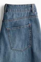 Jean wide leg de denim azul con lavado medio, tiro regular, diseño de cinco bolsillos y perneras amplias y rectas.
