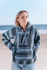 Buzo con capucha a rayas horizontales en tonos celeste y gris oscuro, con bolsillo tipo canguro.