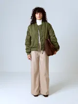 Campera estilo bomber acolchada, color verde militar, con hombros caídos y corte holgado. Presenta cierre frontal metálico y puños y cintura de elástico acanalado.