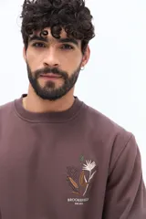 Buzo de algodón azul marino, corte regular, con cuello redondo. Presenta un bordado de flores y texto en el pecho.