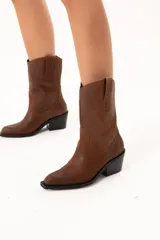 Bota de caña media con diseño estilo western, confeccionada en cuero con acabado texturado craquelado. Presenta tiradores laterales, puntera redondeada y taco cuadrado de altura media.
