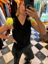 Top negro de taffeta con cuello en V y botones frontales. Presenta plumas de color lima en los hombros.