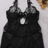 Babydoll corto transparente de encaje negro con aro de realce, aberturas en el escote y ligas incorporadas. Incluye tanga a juego.