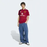 Camiseta de fútbol Adidas del Manchester United, modelo Home 26/27. Diseño en color rojo con cuello polo y puños a rayas en blanco y negro, con detalles de las tres tiras de Adidas en los hombros y el logo de Snapdragon en el frente.