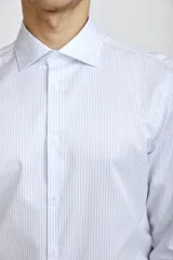 Camisa de vestir blanca de corte clásico, con cuello rígido, cierre frontal de botones y mangas largas con puños abotonados.