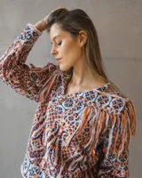 Sweater de punto con diseño étnico multicolor, cuello redondo y detalle de flecos en los hombros. Presenta mangas largas y un ajuste holgado.