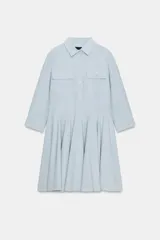 Vestido corto tipo camisero de algodón, con cuello solapa, mangas tres cuartos y cierre frontal con botones. Presenta bolsillos de plastrón con solapa en el pecho y falda con bajo plisado.