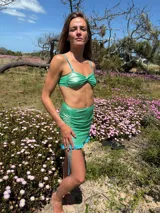 Minifalda verde brillante con frunces laterales y volados en el ruedo.