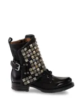 Bota corta de cuero negro con cordones y cierre lateral. Presenta una solapa con tachas plateadas y correa con hebilla en el tobillo.