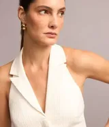 Chaleco blanco de tweed texturizado con espalda abierta, botones delanteros y solapas.